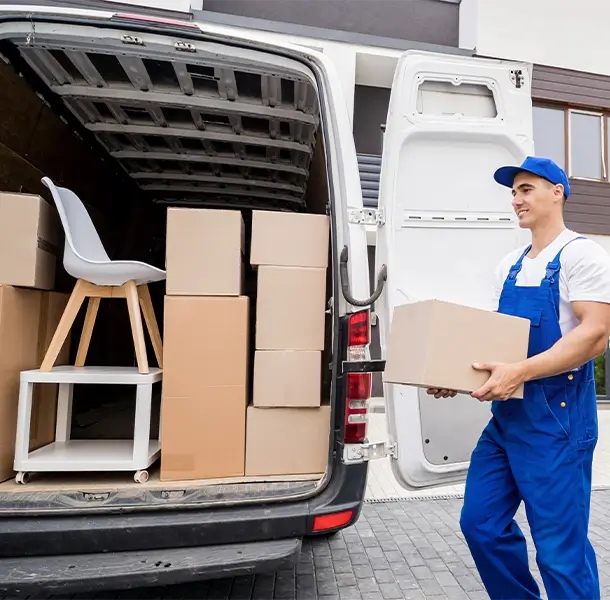 Zwei Umzugshelfer tragen ein graues Sofa in einem modernen Raum mit hellen Wänden und minimalistischer Einrichtung.